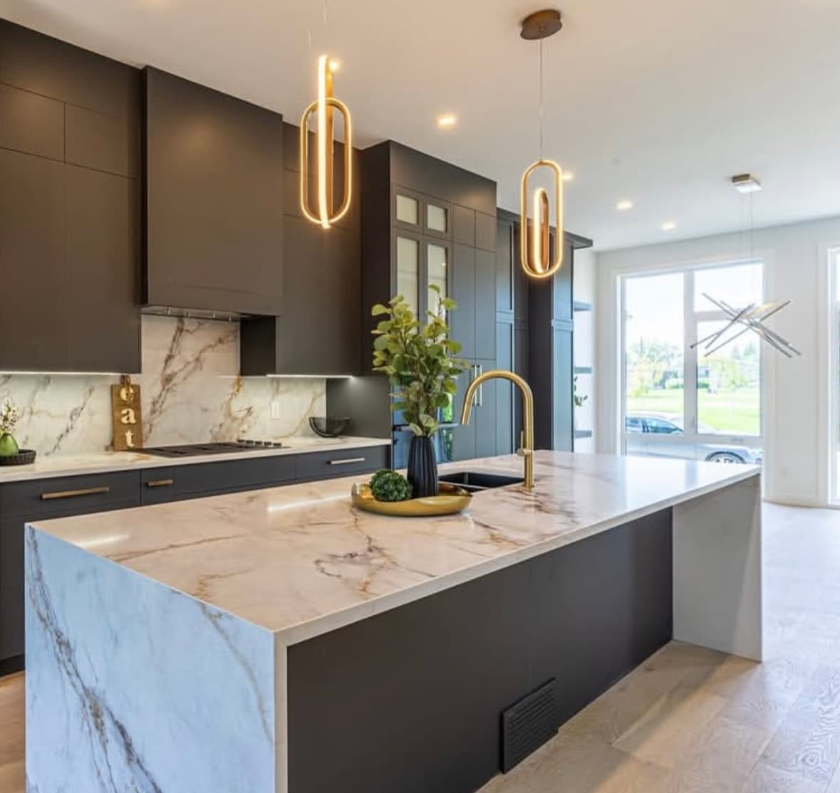 A finished kitchen with a stone island and dark custom cabinetry